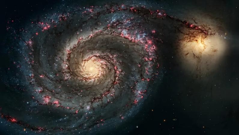 Galáxia espiral M51, ou Galáxia do Redemoinho, com braços espirais azuis e avermelhados, e uma galáxia menor amarelada interagindo à direita, em um fundo escuro com estrelas distantes