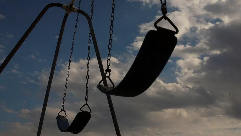 Balanços vazios em dia de céu aberto, sem crianças por perto
