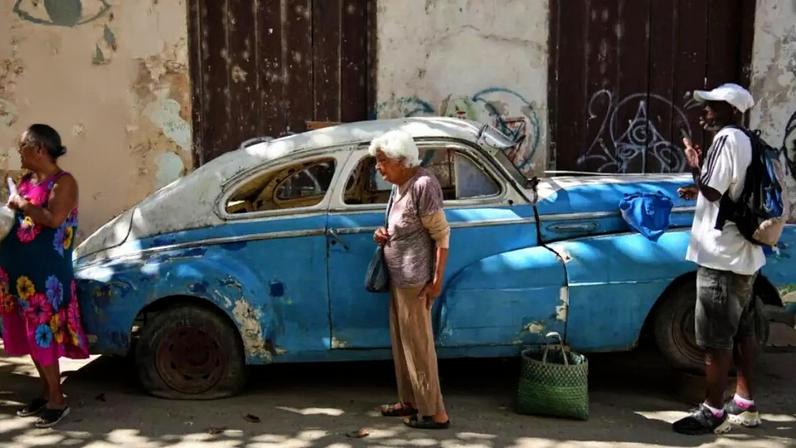 Pessoas passam por um carro clássico americano com pneu furado em Havana Velha, Cuba, na terça-feira, 6 de janeiro de 2026.