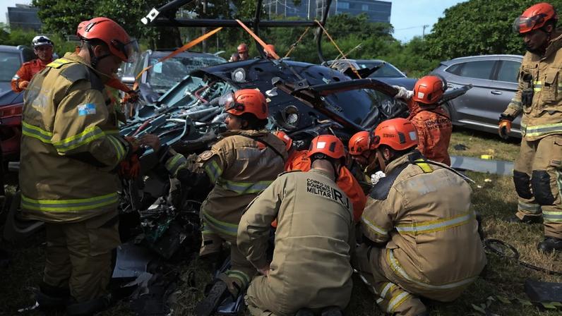 Bombeiros atuam no estacionamento da BYD, onde dois helicópteros caíram após colidirem no Recreio dos Bandeirantes, no Rio de Janeiro.14/06/2026 (Ângela Góes / CBMERJ/Divulgação)