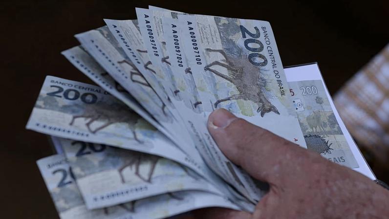 Homem segura várias notas de R$ 200