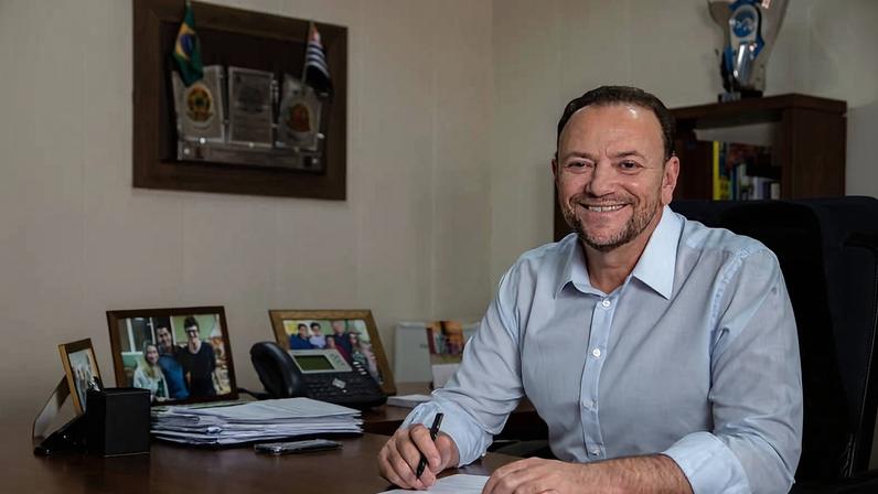 O prefeito de Araraquara, Edinho Silva (PT), sentado à mesa de seu gabinete com uma caneta na mão sobre um papel