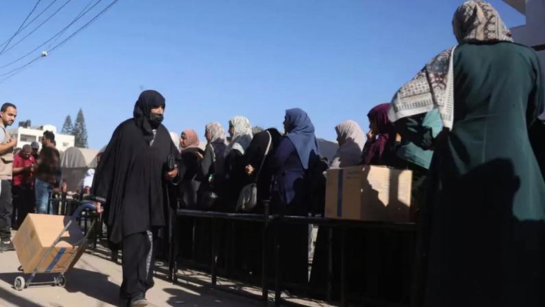 Una palestina transporta una caja de comida proporcionada por el Programa Mundial de Alimentos (PMA) el 27 de octubre de 2025 en un centro de distribución en Al Zawayda, en el centro de la Franja de Gaza