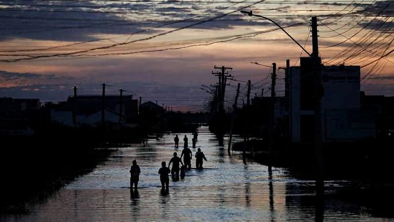 Pessoas caminham em via inundada na cidade gaúcha de Eldorado do Sul, em maio de 2024