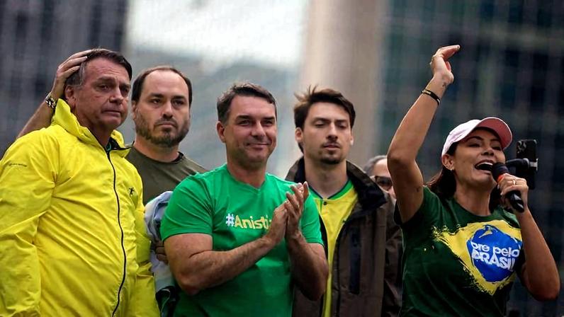 Michelle Bolsonaro (PL) discursando em palanque ao lado de Jair Bolsonaro (PL) e filhos do ex-presidente durante ato na avenida Paulista