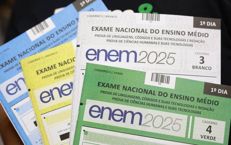 Quatro cadernos do Exame Nacional do Ensino Médio (ENEM) 2025 para o primeiro dia, nas cores branco, verde, amarelo e azul, com títulos indicando provas de linguagens, códigos, redação e ciências humanas.