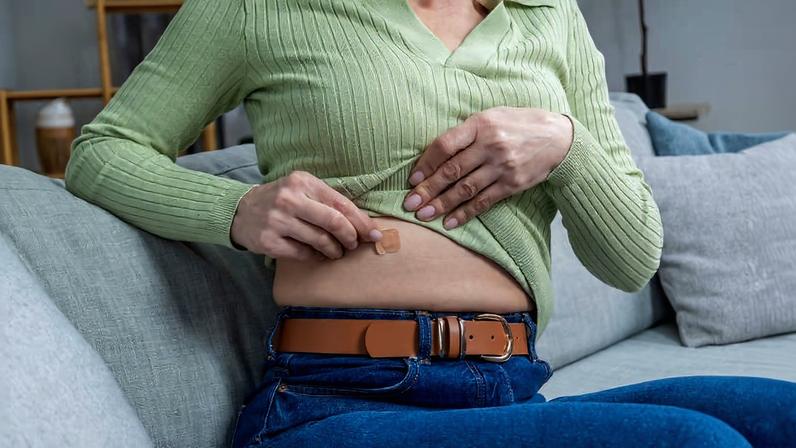 Mulher aplica adesivo de reposição hormonal na barriga