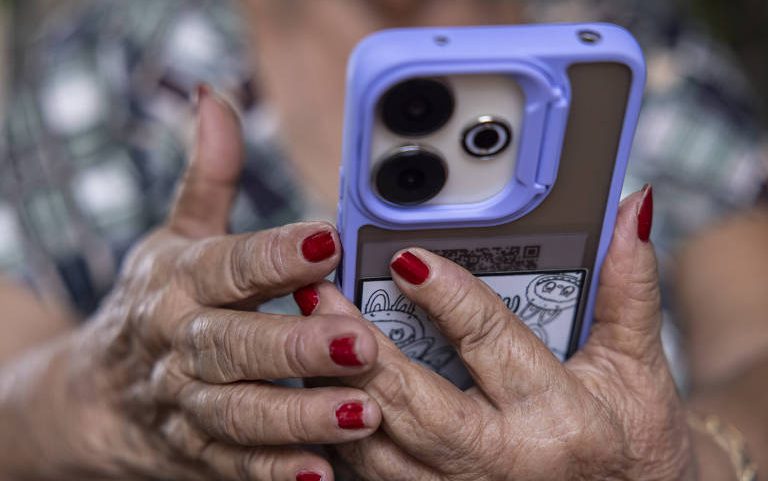 Maria das Graças Rodrigo de Carvalho, aposentada, mexe no celular, em sua casa, na cidade de Breves (PA)