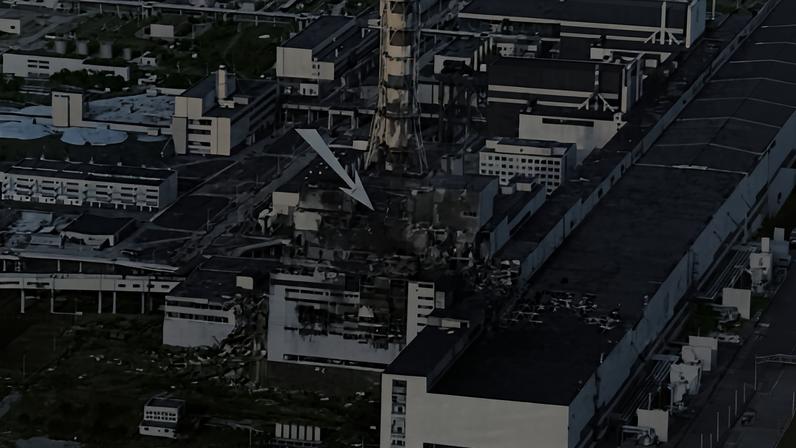 Vista aérea em preto e branco da Usina Nuclear de Chernobyl mostrando danos extensos no reator 4, indicado por uma seta branca. Estruturas industriais e prédios adjacentes aparecem intactos, com a chaminé do reator visível ao centro.