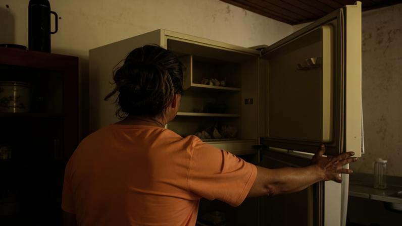 Lúcia Audibert, 54, agricultora de hortaliças, mostrando sua geladeira, que, após parte de sua casa ser invadida pela água devido à enchente, agora é usada como armário
