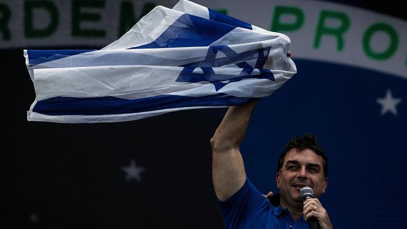 O senador e pré-candidato à presidência da República Flávio Bolsonaro levanta a bandeira de Israel na Marcha para Jesus, em São Paulo