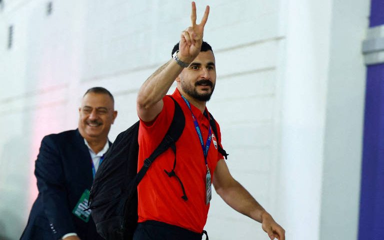 Aymen Hussein acena para torcedores; atacante teria sido interrogado por 7 horas antes de ser liberado para entrar nos EUA, onde disputará a Copa