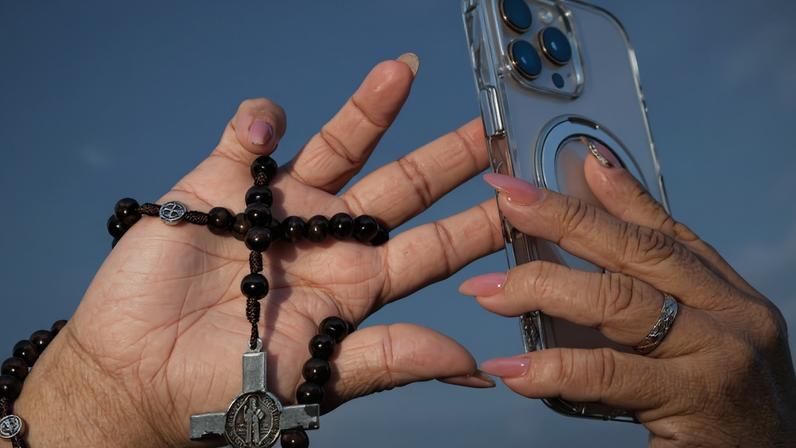 Um terço e um celular, trazidos por um fiel para o primeiro discurso do papa Leão 14 na Basílica de São Pedro, na Cidade do Vaticano