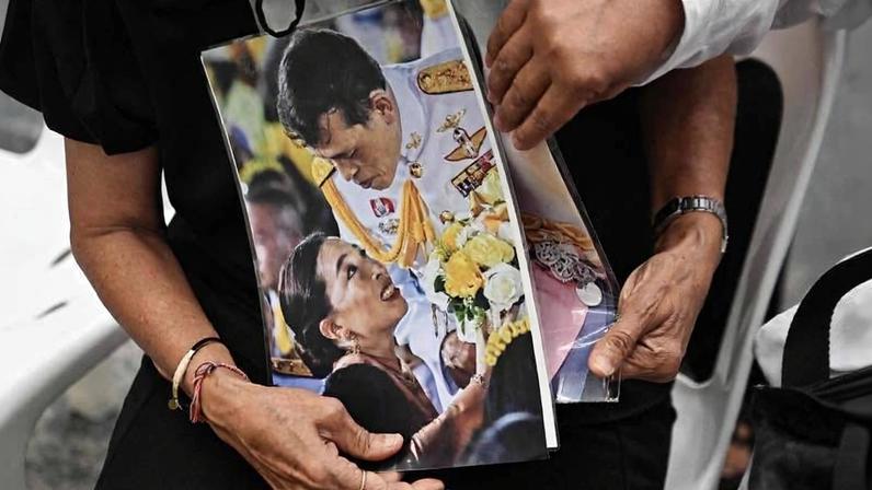 Moradora em luto segura fotos da princesa tailandesa Bajrakitiyabha Mahidol e de seu pai, o rei Maha Vajiralongkorn, dentro de hospital em Bangkok