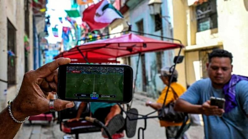 Torcedores cubanos da seleção mexicana de futebol assistem à partida de abertura da Copa do Mundo entre México e África do Sul em seus celulares, em Havana