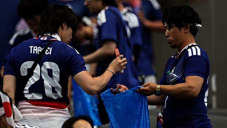 Torcedores japoneses recolhem lixo de estádio após partida contra a Holanda, no domingo (16)