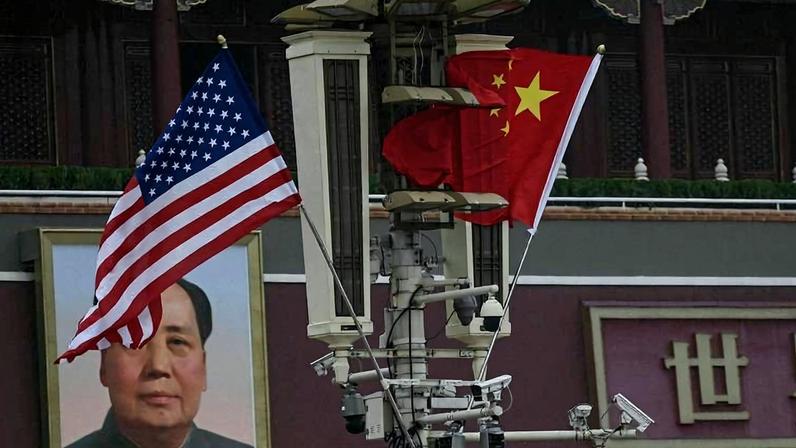 As bandeiras nacionais dos EUA e da China penduradas diante do retrato do líder comunista Mao Tsé-tung, em Pequim