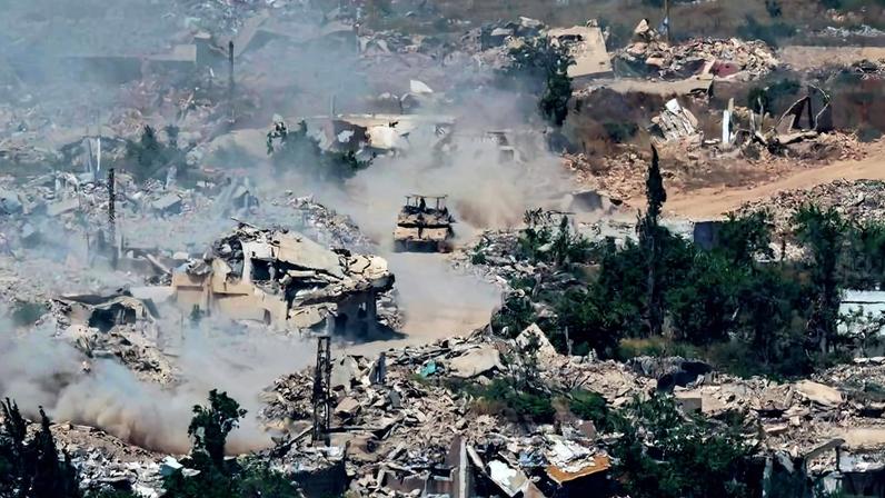 Tanques israelenses andam em meio a destroços de prédios destruídos por ataques de Israel no sul do Líbano
