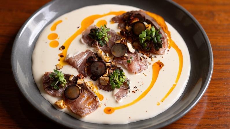 Peixe semicurado servido sobre o tradicional creme ajoblanco, do Huevos de Oro