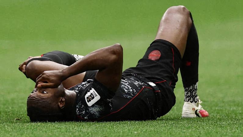 Ismael Koné caído no gramado, com a perna quebrada, após falta de Assim Madico do Qatar