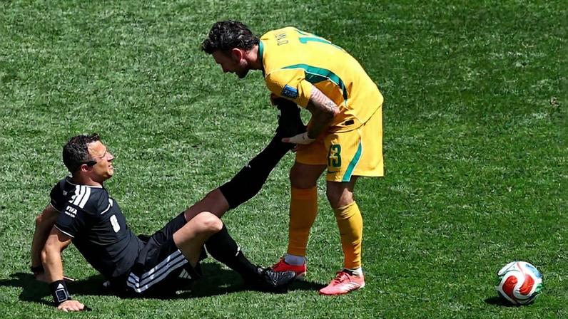 Felix Zwayer é socorrido pelo jogador Aiden O'Neil, da Austrália; árbitro alemão recebeu atendimento médico após sentir dores, mas conseguiu prosseguir na partida.