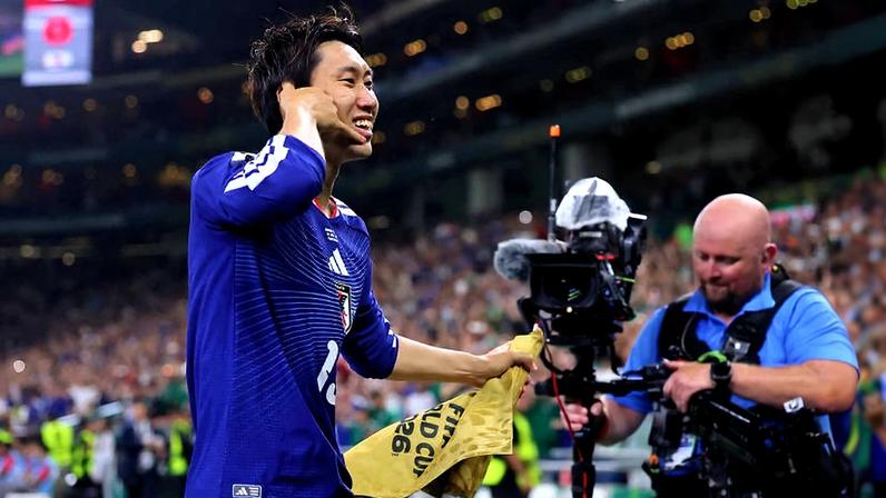 Kamada comemora o seu gol, o primeiro do Japão logo aos 3min de jogo, fingindo um telefonema e segurando a bandeira de escanteio