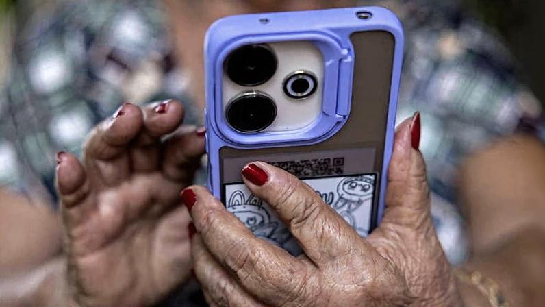 Maria das Graças Rodrigo de Carvalho, 76, aposentada, mexe no celular em sua casa