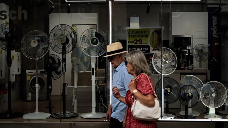 Homem e mulher passam diante de loja com ventiladores à venda em Madri, na Espanha nesta quinta-feira (25)