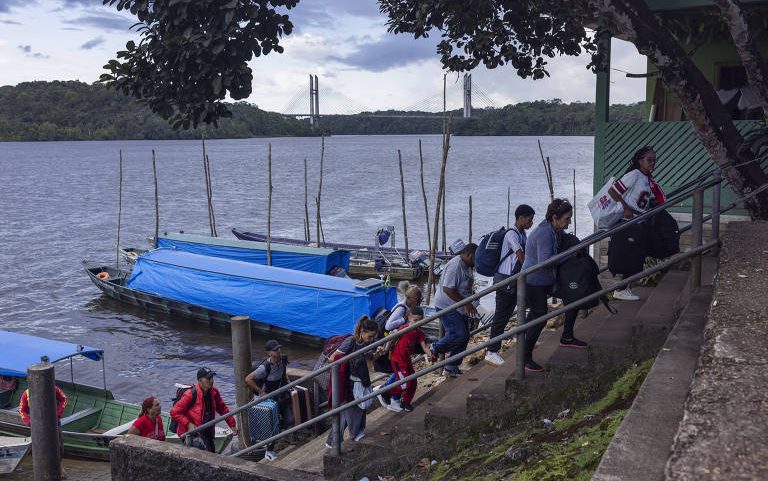 Migrantes desembarcam na orla de Oiapoque, no Brasil, depois de atravessarem o rio vindos da Guiana Francesa