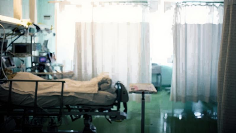 Paciente ligado a aparelhos em leito de hospital