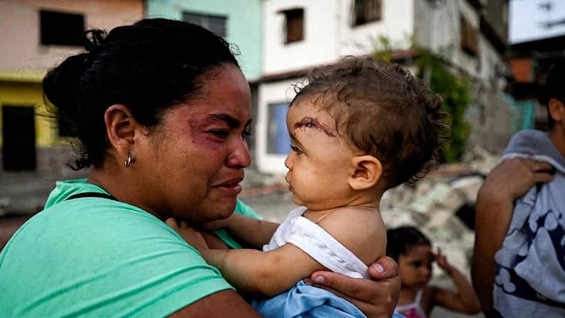 Uma mulher se emociona enquanto carrega uma criança ferida após os terremotos em La Guaira