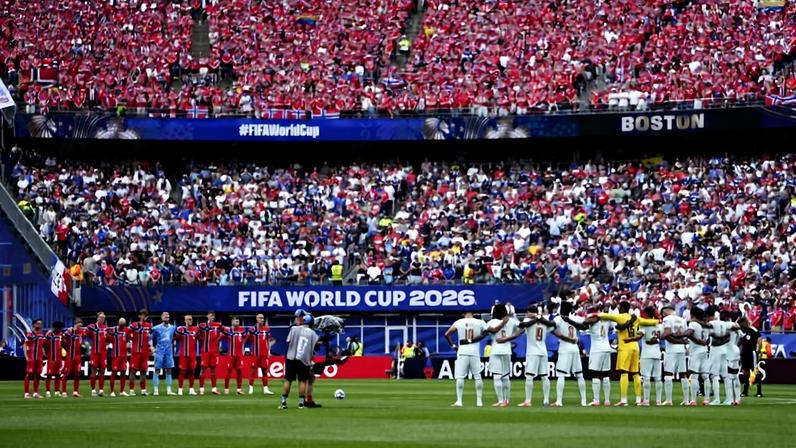 Duas equipes de futebol alinhadas no campo antes do início da partida na Copa do Mundo FIFA 2026. Uma equipe veste uniforme vermelho e a outra branco. No fundo, arquibancadas lotadas com torcedores, muitos vestindo vermelho, e faixas com inscrições 'FIFA World Cup 2026' e 'Boston'.