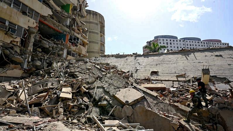 Socorristas caminham sobre escombros de prédio que caiu durante terremoto em La Guaira, na Venezuela