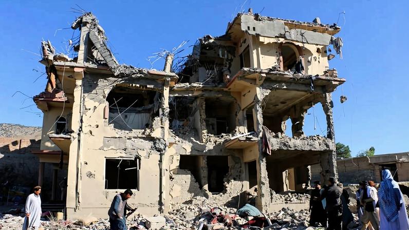 Moradores e membros do Talibã se reúnem perto de um prédio destruído no Afeganistão após um ataque aéreo que, segundo o Talibã, foi realizado pelas forças de segurança do Paquistão