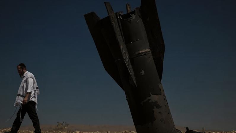 Judeu ultraortodoxo se afasta dos restos de um míssil balístico iraniano em campo aberto, no vale do rio Jordão
