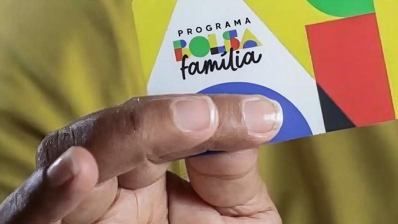 Homem segurando cartão do Bolsa Família.