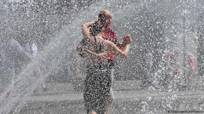 Casal dança em meio a refresco proporcionado por chafariz em Munique, sul da Alemanha
