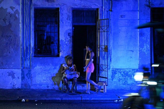 Moradora de Havana checa o celular durante blecaute, no centro da capital cubana: apagões causados por bloqueio dos EUA - (crédito: Adalberto Roque/AFP)