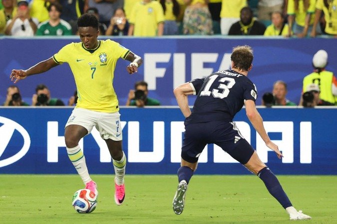 O atacante brasileiro Vinicius Junior (nº 7) e o defensor escocês Jack Hendry (nº 13) disputam a bola durante a partida de futebol do Grupo C da Copa do Mundo de 2026 entre Escócia e Brasil, no Miami Stadium, em Miami Gardens, em 24 de junho de 2026