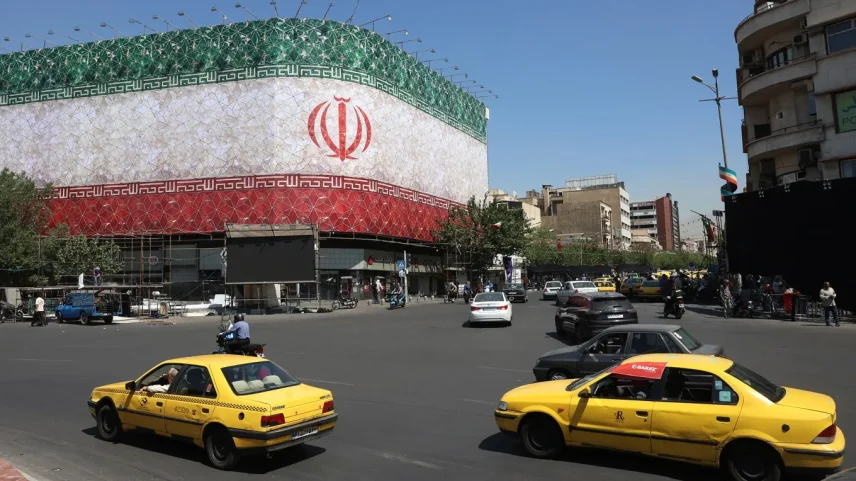 Traffic moves past the Iranian national flag displayed on a building at Enghelab square in Tehran on June 14.