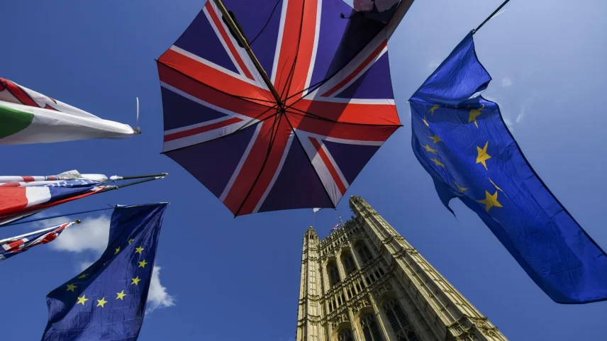 An umbrella featuring the design of the Union flag, also known as the Union Jack, stands near EU flags outside the Houses of Parliament in London.
