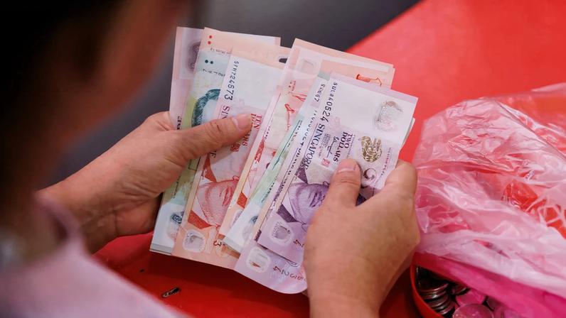 A vendor counts Singapore dollar banknotes at a street market stall in Singapore.