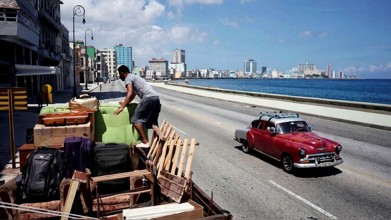 A man loads a truck with furniture from his home prior to the arrival of Storm Elsa, in Havana