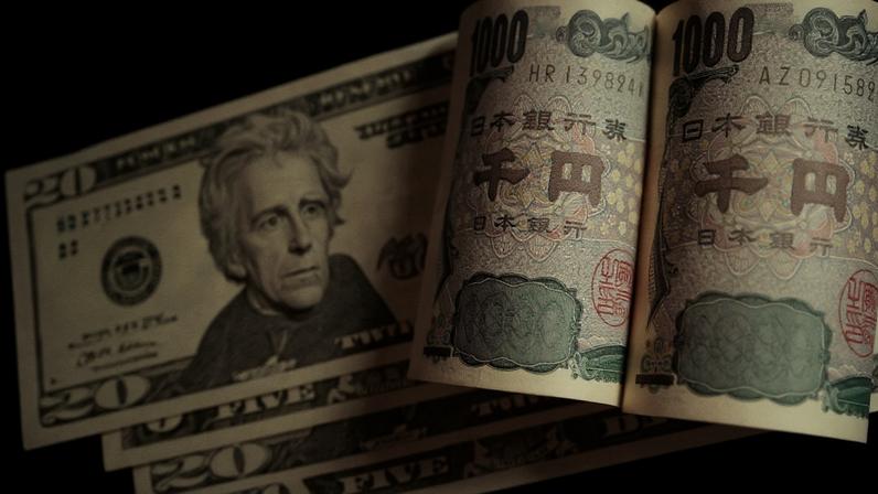 Cédulas de dólar e duas cédulas de 1000 ienes japoneses enroladas, sobre fundo escuro.