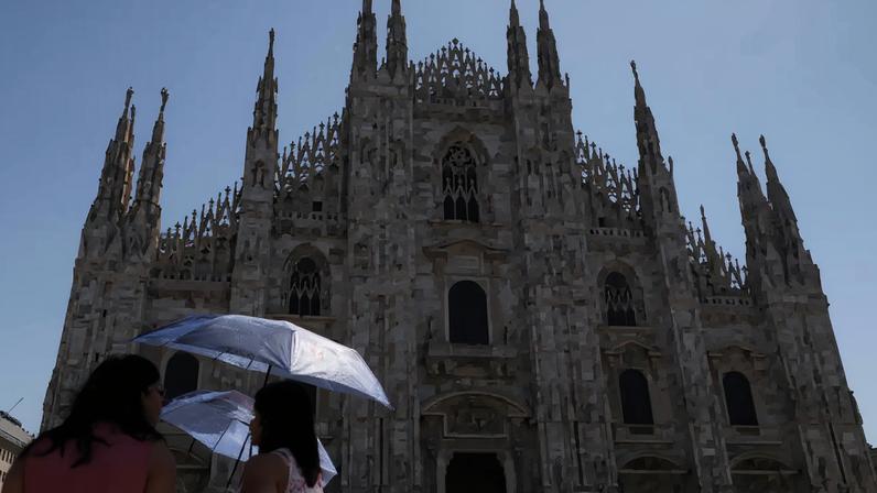 Turistas se protegem do sol com um guarda-chuva durante uma onda de calor perto da Catedral Duomo, em Milão, Itália, em 26 de maio de 2026.