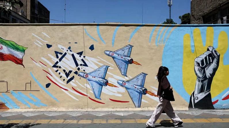 Mulher passa em frente a mural sobre a guerra em Teerã — Foto: Majid Asgaripour/WANA
