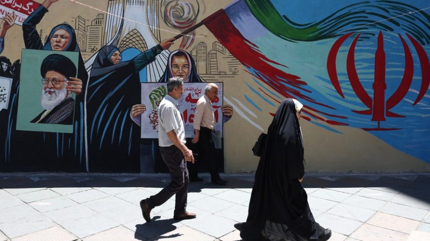 Pessoas caminham por uma rua perto de um mural com a imagem do falecido Líder Supremo do Irã , Aiatolá Ali Khamenei, em Teerã, Irã , 1º de junho de 2026