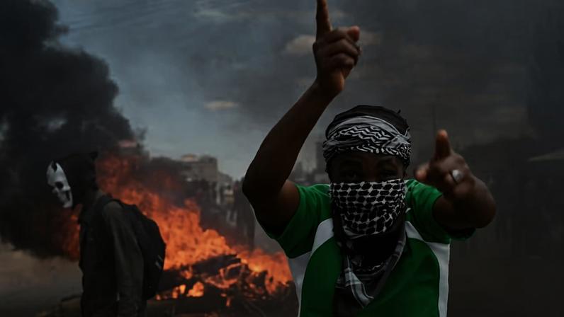 Um manifestante gesticula enquanto ergue uma barricada durante um protesto contra um plano de quarentena apoiado pelos EUA para o Ebola. O plano previa a instalação de um centro com 50 leitos em uma base da Força Aérea do Quênia , destinado a abrigar americanos expostos ao Ebola, na cidade de Nanyuki, no condado de Laikipia, Quênia , em 1º de junho de 2026 — Foto: REUTERS/John Muchucha