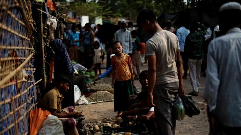 Um refugiado rohingya observa um mercado à beira da estrada dentro de um campo de refugiados em Cox's Bazar, Bangladesh, 17 de abril de 2026