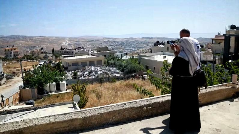 Pessoas observam de um telhado os escombros de um prédio palestino demolido por militares israelenses na cidade de Jabaa, na Cisjordânia ocupada por Israel , perto de Jerusalém , em 3 de junho de 2026